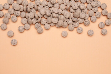 Beer yeast pills on pale orange background, flat lay. Space for text