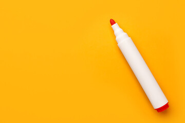 Bright red marker on orange background, top view. Space for text