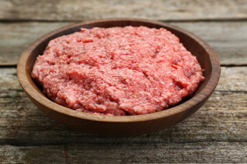 Bowl with raw fresh minced meat on wooden table, closeup