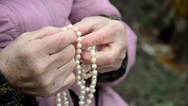 Old hands with pearl beads. Pearls in old hands. Necklace in old hands. The concept of the elderly. Caring for the elderly. Charity. Aged people. Wrinkled hands of an old woman.
