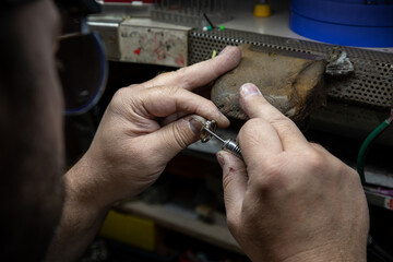 Un artigiano realizza a mano un anello in oro., fase di pulitura e lucidatura. 