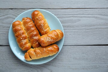 Delicious sausage rolls on grey wooden table, top view. Space for text