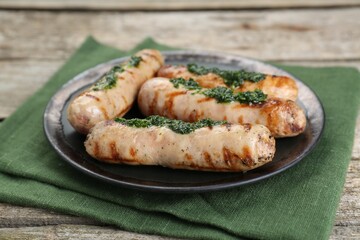 Tasty fresh grilled sausages with sauce on wooden table