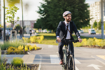 Cheerful employee looking away, while riding on bike path.