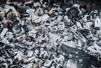Close-up photo of smoldering gray coals, burnt ash close-up in a bonfire, fire.
