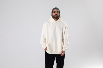 African American man in a knitted hat and white oversized hoodie.