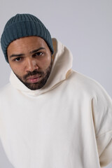African American man in a knitted hat and white oversized hoodie.