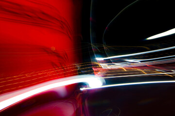 Abstract colorful background with red, white and yellow glowing lines of different thickness and curvature from city lights on a black background. The blur is intentional.