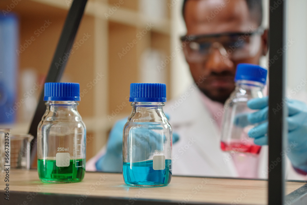 Wall mural small bottles with colorful reagents on shelf in laboratory