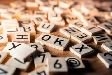 Close up of jumbled series of letters on a wooden table with the word OK clearly visible. Concept of affirmation, accept, approval. Copy space wooden letters.