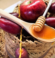 Ripe red apple, fresh dates and honey. Healthy natural food for humans, full of vitamins. Jewish New Year - Rosh ha Shana food symbols. Wood honey dipper and spoon against old rustic straw farmer hat