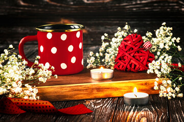 Red cup with white polka dots, candles, red knitted heart, gypsophila flowers and red ribbon....
