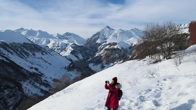 Young female adventure photographer taking pictures around the snowy mountains