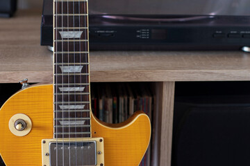 Obraz premium A yellow les paul electric guitar resting against a collection of vinyl music and a turntable.