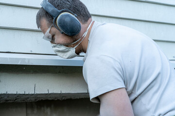 View of a dirty man in protective earcklocks, mask and glasses.