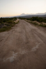 View of the empty dirt road across the hills at sunset.