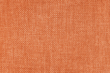 Jacquard woven upholstery, orange coarse fabric texture. Textile background, furniture textile material, wallpaper, backdrop. Cloth structure close up.