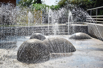 Water spraying and splashing from vertical jets and ground spray nozzles at a splash pad in the...