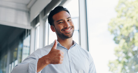 Fototapeta premium Businessman, thumbs up and wink while walking in office for success, motivation or thank you. Face portrait, yes and male employee from Singapore with hand gesture for support, like emoji or approval