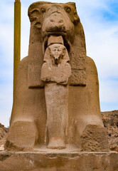 Closeup of pharaoh between the feet of a sphinx at the Temple in Karnak, Egypt.