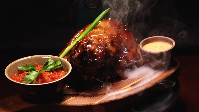 pork knuckle in smoke. rotation around its axis against a black background.
