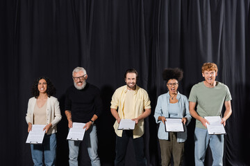 multicultural actors with bearded screenwriter holding clipboards and grimacing at camera during...