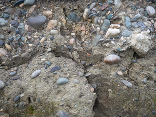 Layers of earth on a beach made of pebbles. Soil cut. Cobblestones and earth. After the excavator.