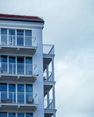 White building with balconies and windows near the sea on a cloudy day