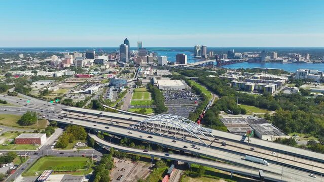 Aerial view of Jacksonville city with high office buildings and american freeway intersection with fast moving cars and trucks. USA transportation infrastructure concept