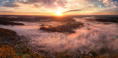 Fototapeta na wymiar Glorious sunrise over the mist, an aerial panorama of a town on a majestic morning