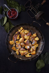 Traditioneller österreichisch Kaiserschmarren mit Rosinen und Puderzucker serviert als Draufsicht in einer rustikalen schmiedeeisernen Bratpfanne mit Textfreiraum