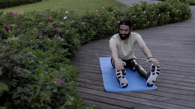 Fit man with disability wearing bionic hi-tech leg prosthesis while doing workout sport routine outdoor