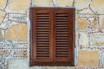 Close-up wall of a stone house with wooden windows and shutters. Old european architecture
