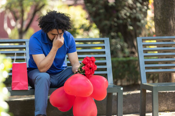 mexican man sitting on park bench crying on valentine day, bad date