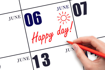 Hand writing the text HAPPY DAY and drawing the sun on the calendar date June 6