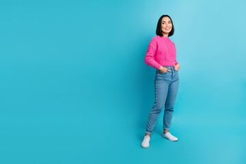 Full size photo of cheerful lovely girl put hands pockets look empty space isolated on blue color background