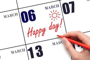 Hand writing the text HAPPY DAY and drawing the sun on the calendar date March 6