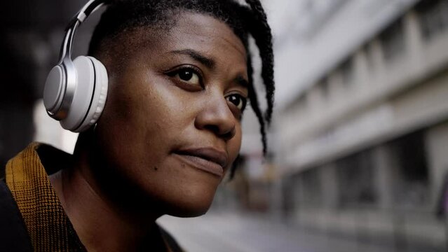 African young woman listen playlist music while waiting at bus station outdoor