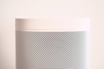 Close shot of a white audio speaker in front of the white wall