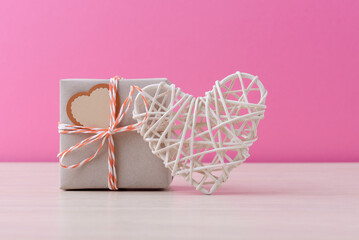 Craft handmade gift box and valentine’s heart over pink background with copy space