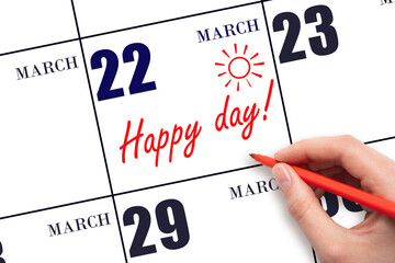 Hand writing the text HAPPY DAY and drawing the sun on the calendar date March 22