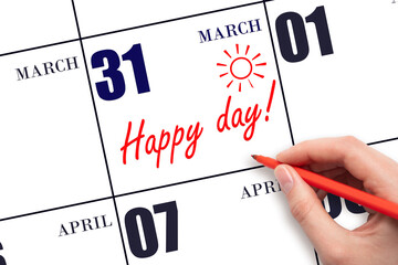 Hand writing the text HAPPY DAY and drawing the sun on the calendar date March 31
