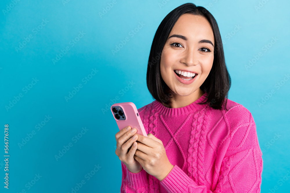 Sticker Portrait of cheerful malaysian lady toothy smile hold telephone empty space isolated on blue color background