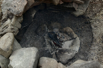 A place for a bonfire made of stones in nature, coals, a bowl with mushrooms.
