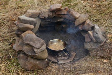 A place for a bonfire made of stones in nature, coals, a bowl with mushrooms.