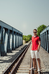 Young Male Model Posing in Red Polo Shirt on Train Tracks. Portrait Photoshoot