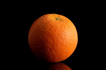 One unpeeled orange, macro, isolated on black background.