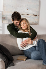 curly young man hugging pleased blonde woman in living room.