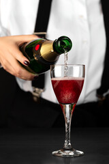 bartender makes a kir royal cocktail on a dark background