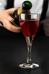 bartender makes a kir royal cocktail on a dark background